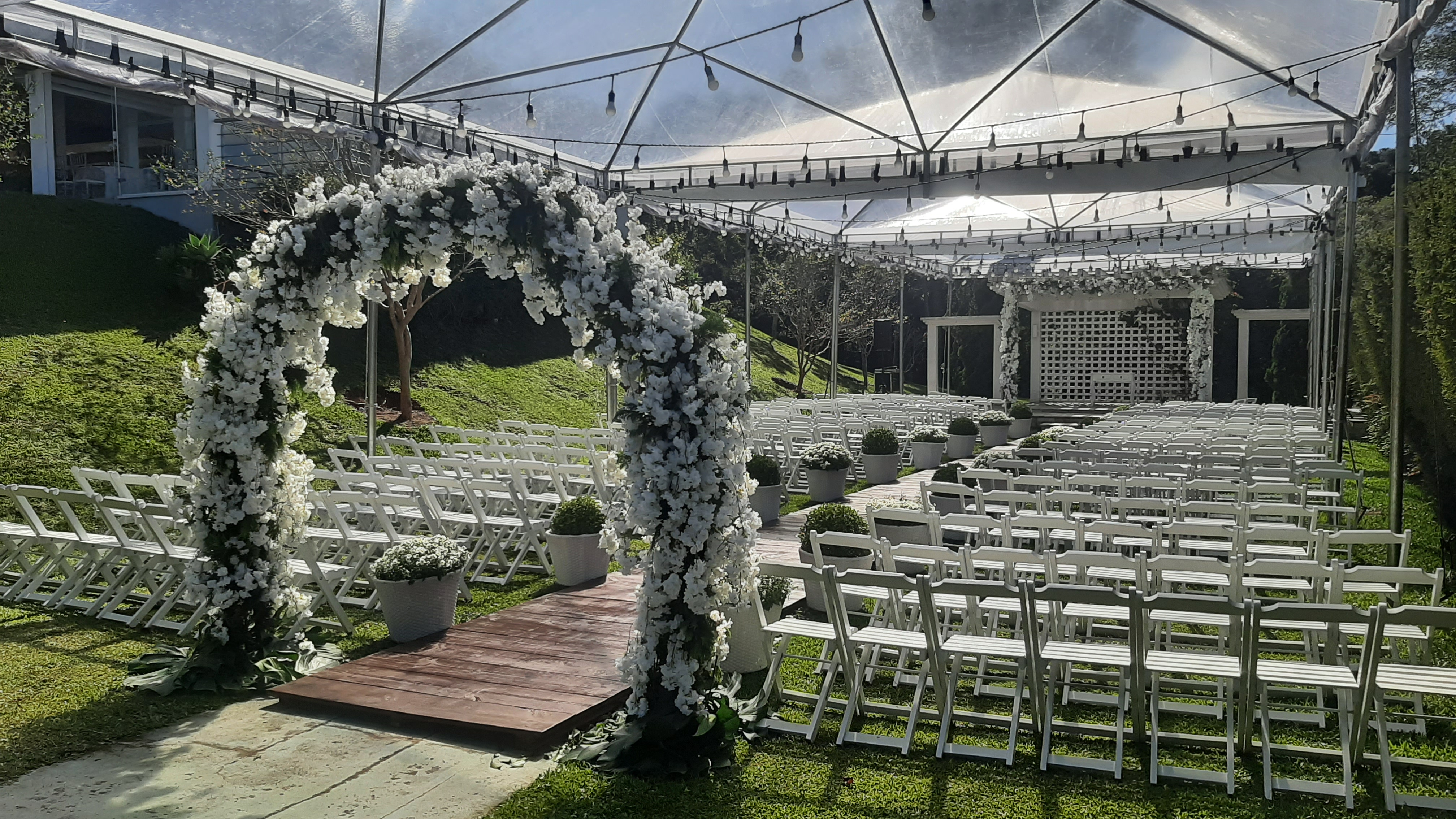 Arco de flores brancas e cobertura iluminada em cerimônia ao ar livre